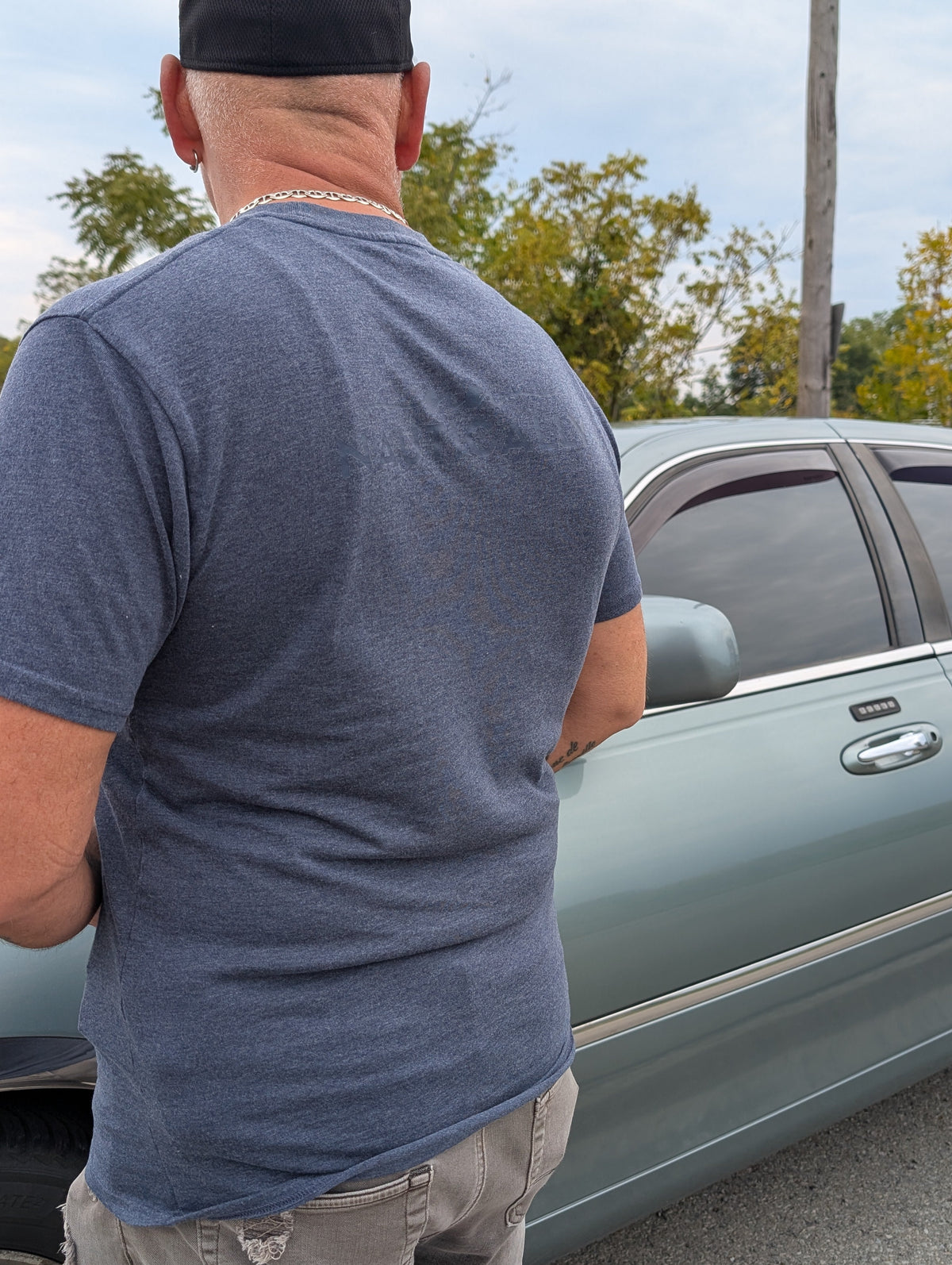 The Coastal Tee in Moormist — profile view by car, showing fit and colour