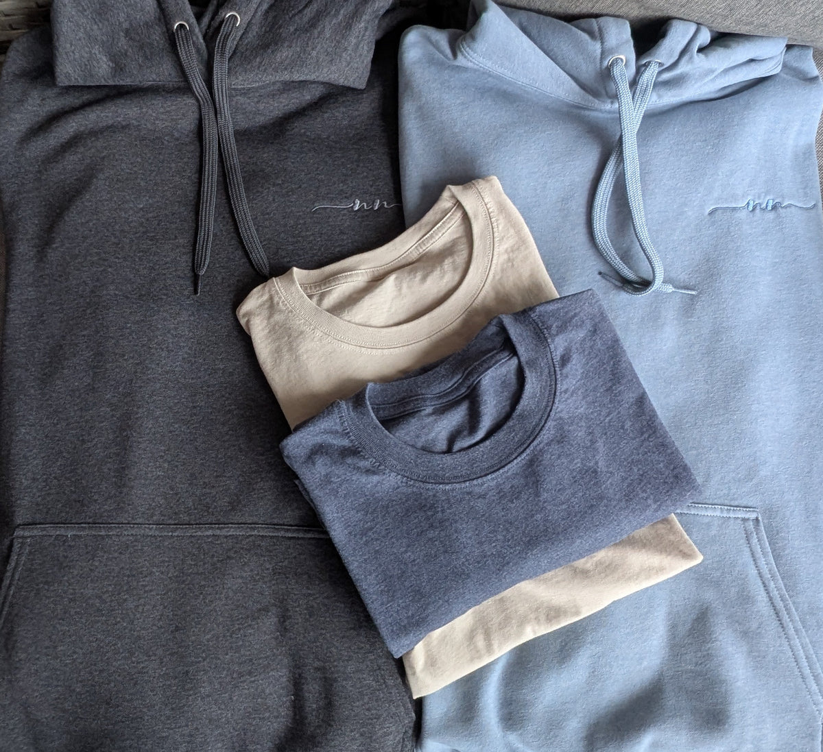 Nautically Nice Coastal Hoodie and Tee flat lay — Nightnoir and Skystone hoodies with Dunedrift and Moormist tees
